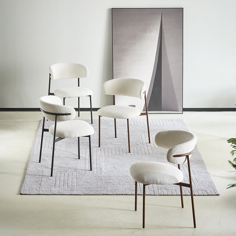 Quattro sedie Zahra in tessuto bouclé attorno a un tavolo da pranzo, design minimalista e neutro