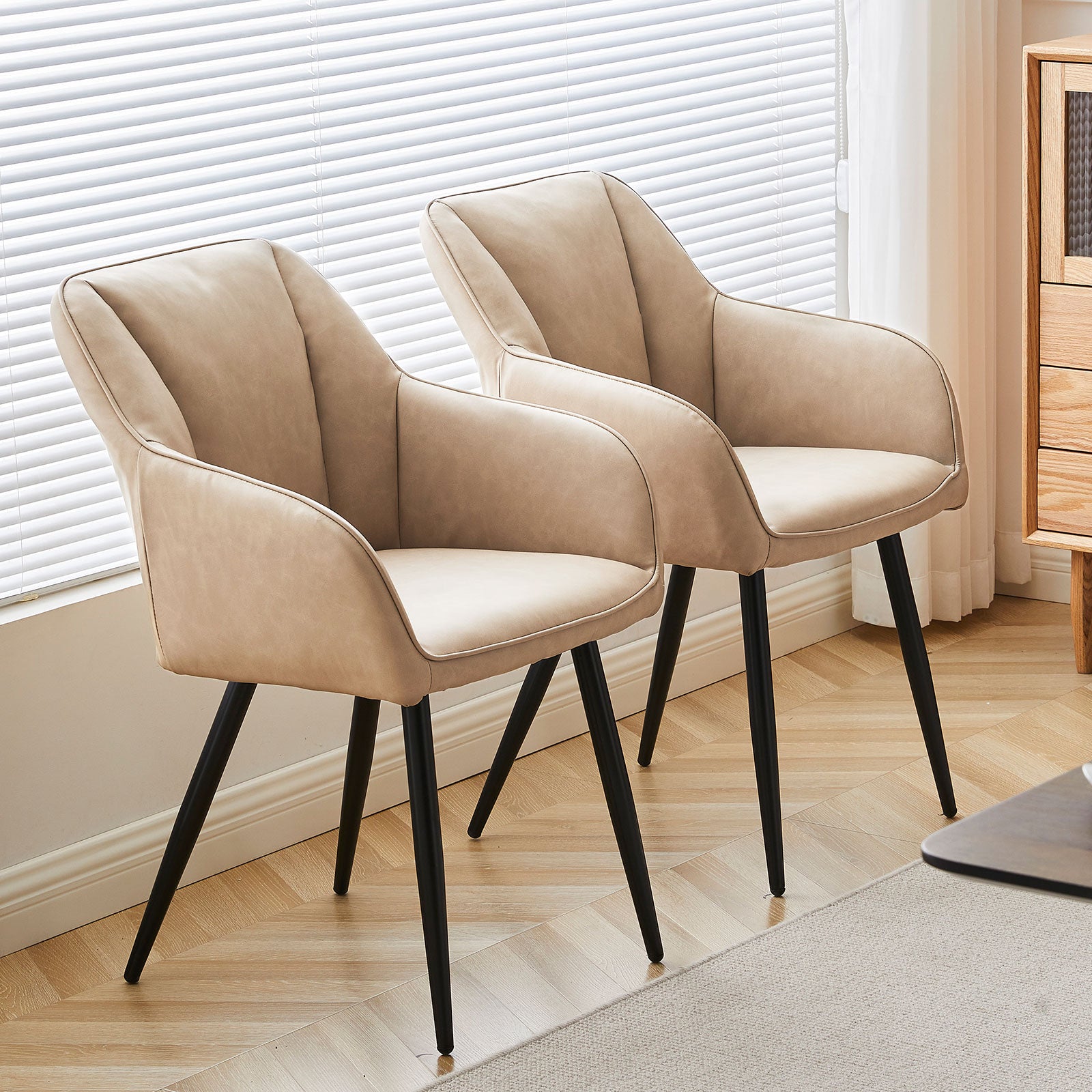 Quattro sedie da pranzo Sienna grigie con rivestimento in tessuto e gambe in metallo nero, posizionate intorno a un tavolo in legno，Sedia Sienna in primo piano che mostra lo schienale ergonomico e l'imbottitura premium, perfetta per pranzi prolungati